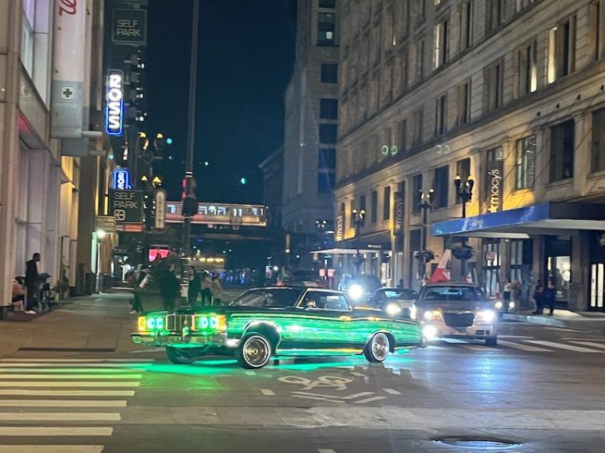 Midnight filming in the Chicago theatre district. A fancy blazing green car with strange wheel sizes on one side clambered through the street.