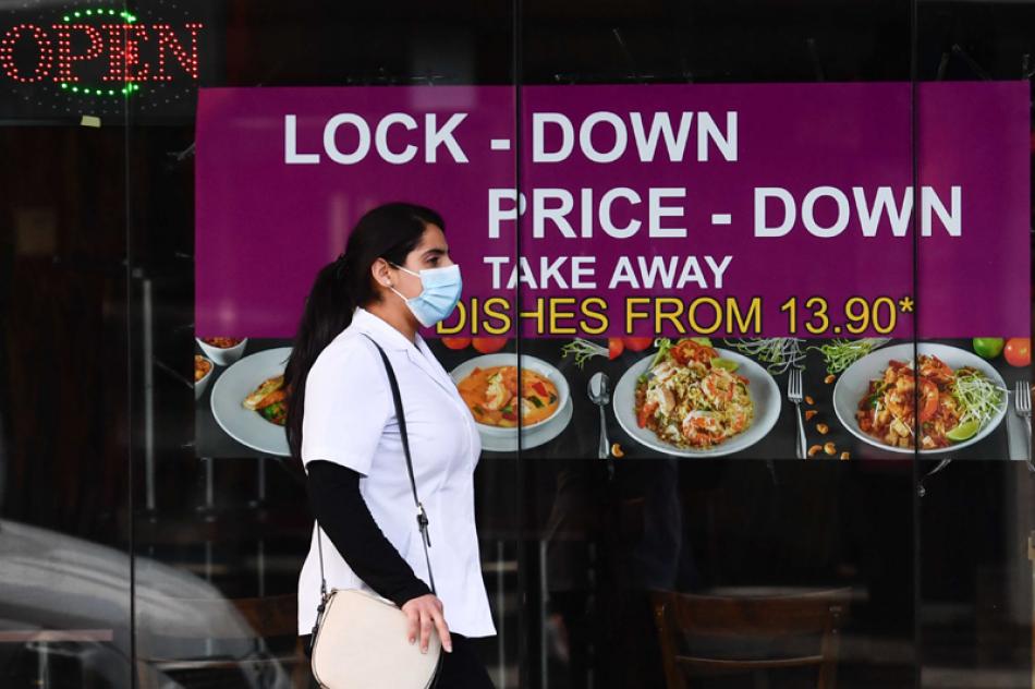 Images of the Day:A woman wearing a face mask walks past a restaurant in Melbourne 