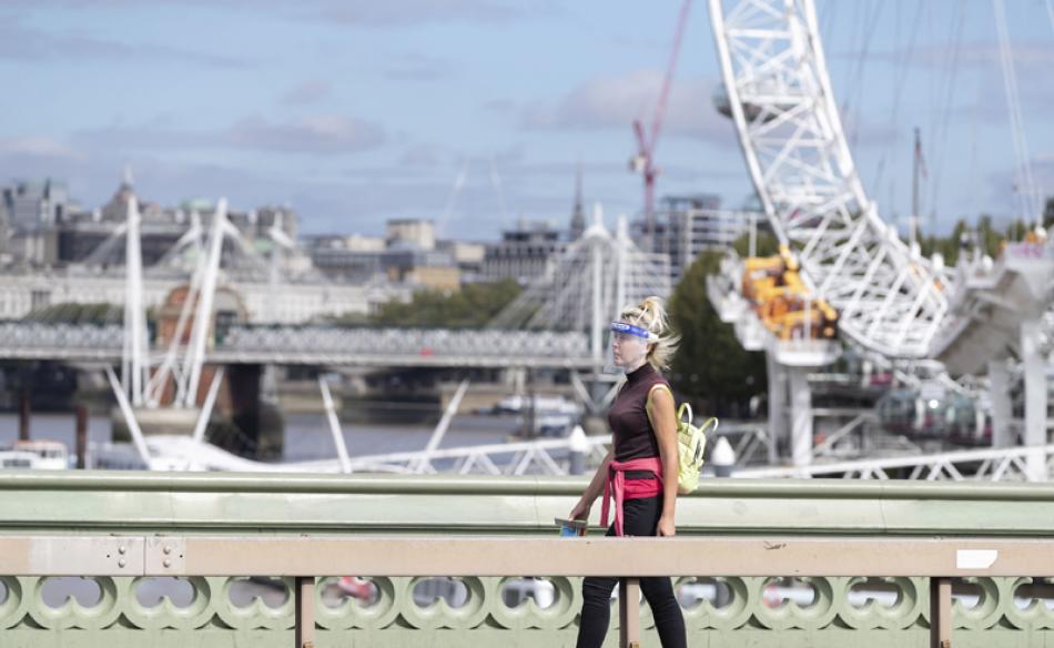 Images of the Day:A woman wearing a face shield walks past the London Eye